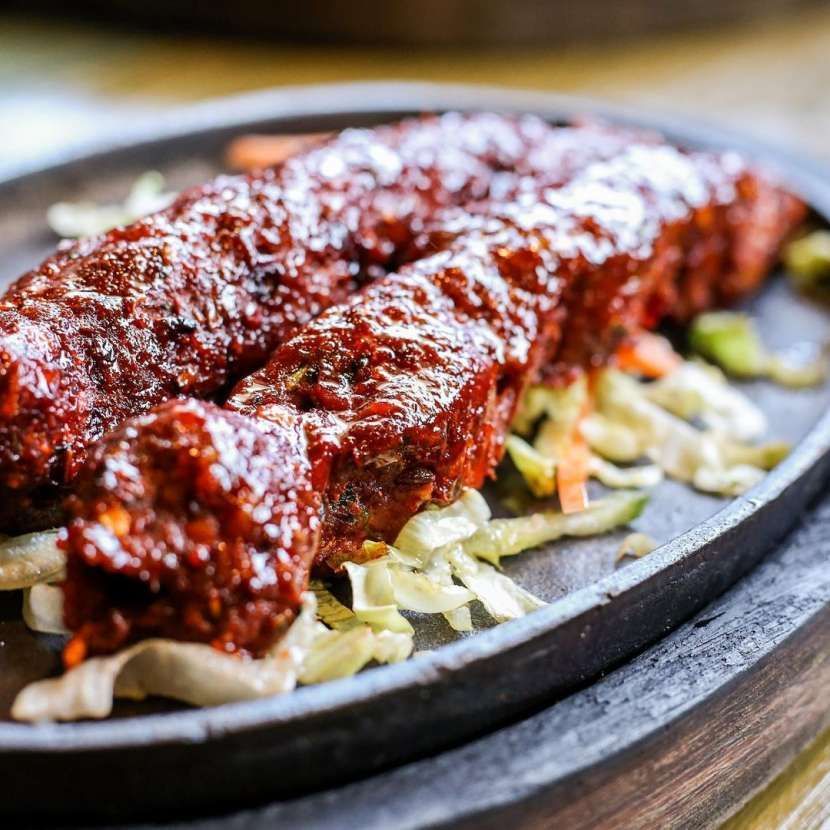 A close up of a plate of food with meat and vegetables on a table.