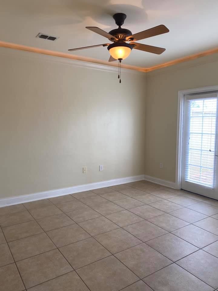 An empty room with a ceiling fan and a sliding glass door.