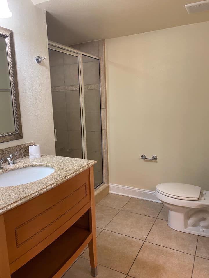 A bathroom with a sink , toilet , shower and mirror.