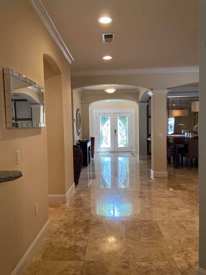 A hallway in a house with marble floors and a mirror on the wall.
