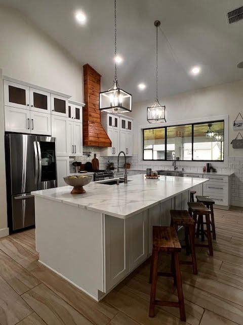 A kitchen with white cabinets and marble counter tops