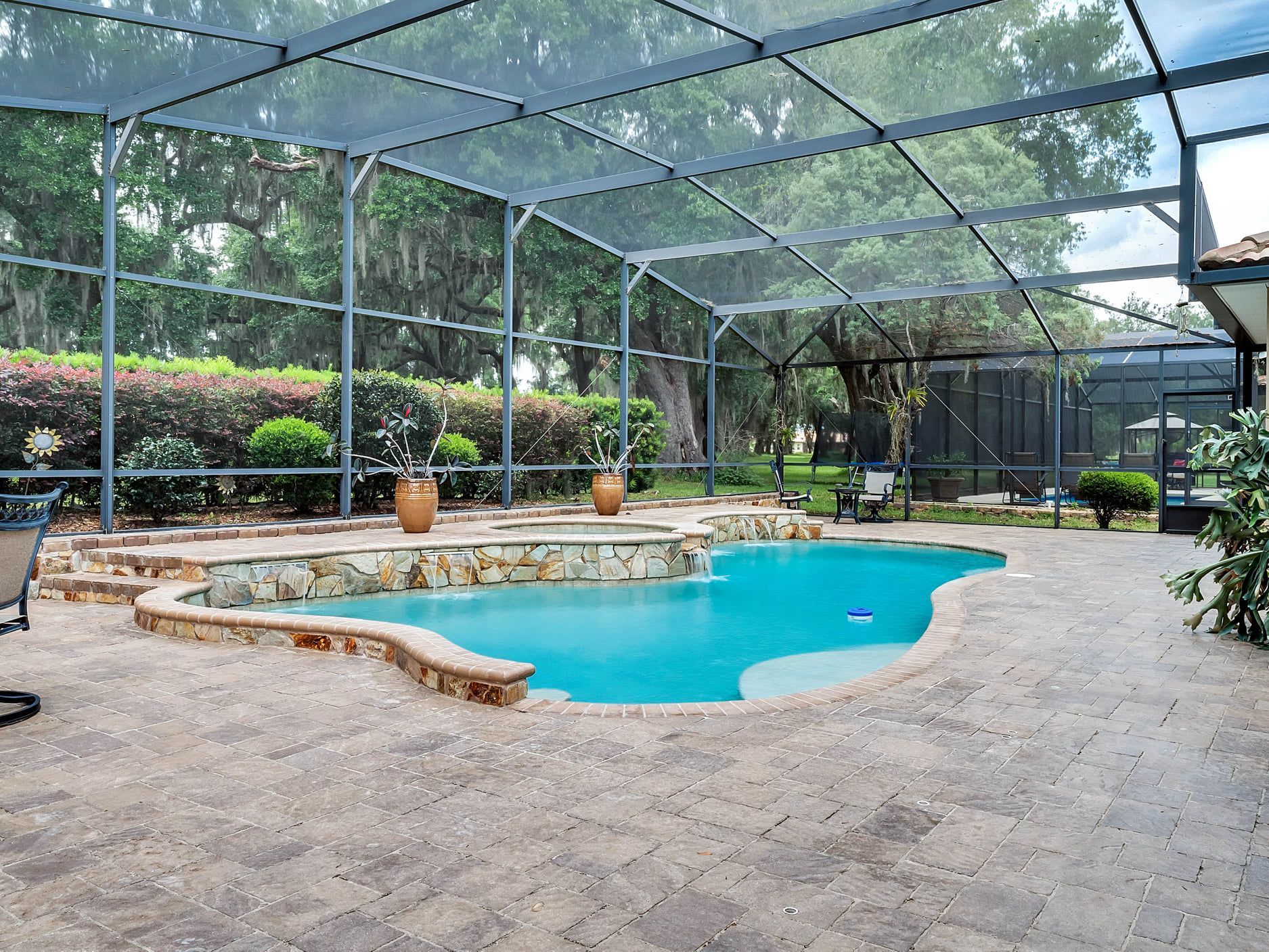 A large swimming pool is surrounded by a screened in area.