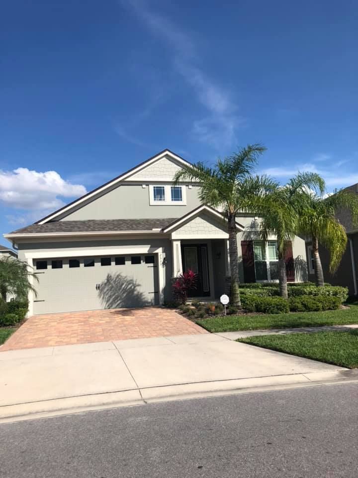 A large house with a driveway and palm trees in front of it