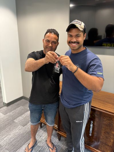 Two men are standing next to each other in a room holding keys.