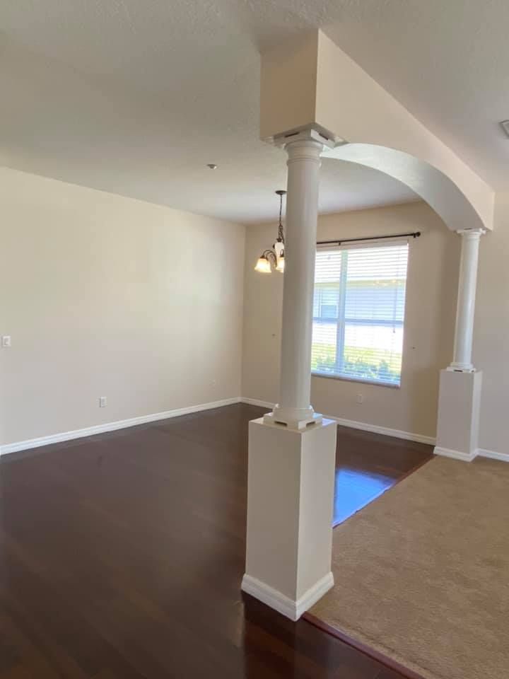 An empty living room with a pillar and a window.