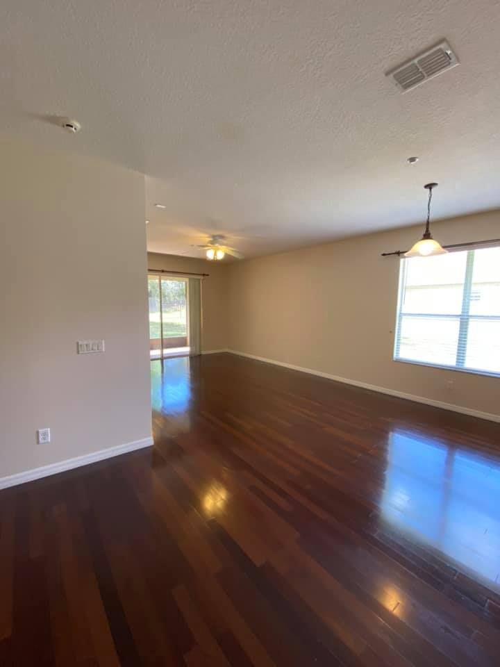 An empty living room with hardwood floors and a ceiling fan.
