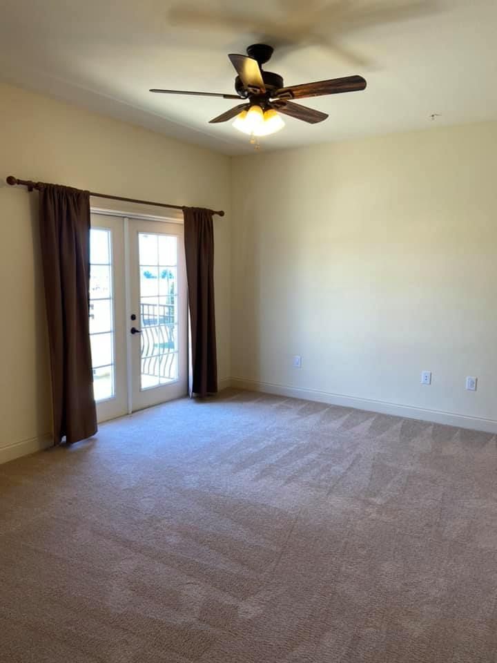An empty room with a ceiling fan and sliding glass doors