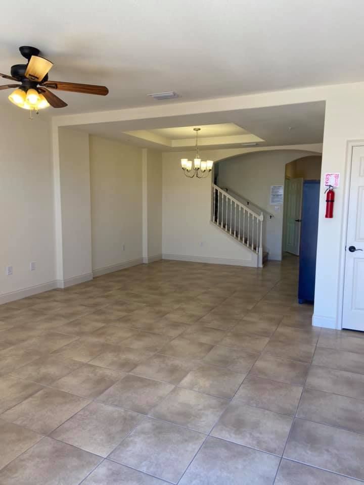 An empty living room with a ceiling fan and stairs