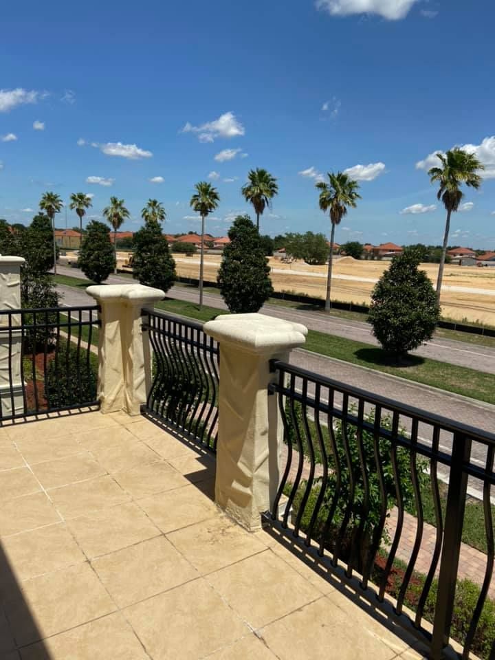 A balcony with a fence and palm trees on a sunny day.