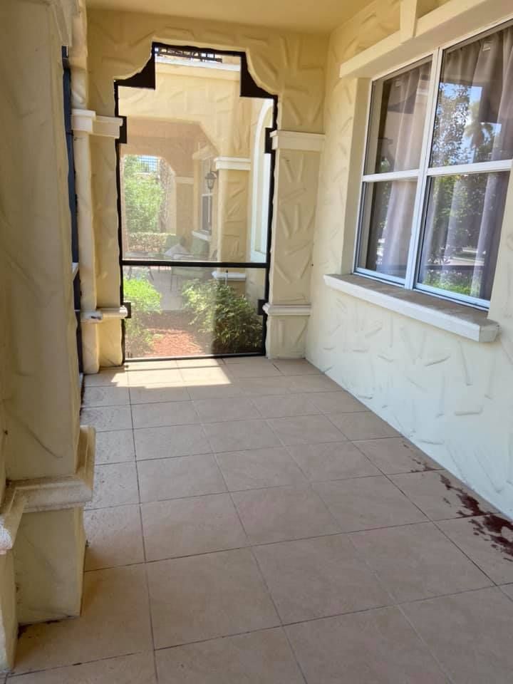 An empty porch with a screen door and a window.