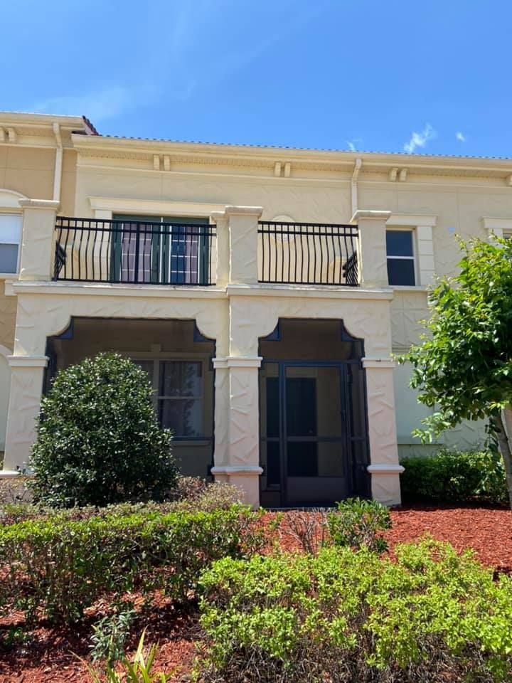 The front of a large house with a balcony and a screened in porch.