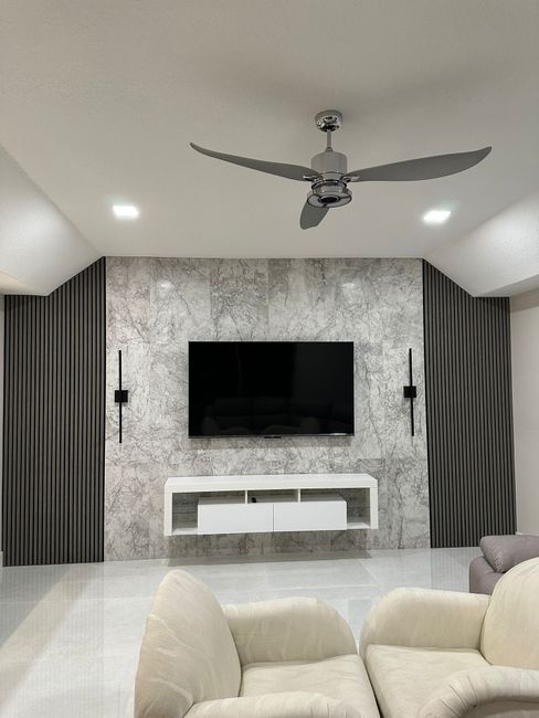 A living room  in Martin County, FL with a ceiling fan and a flat screen tv on the wall.