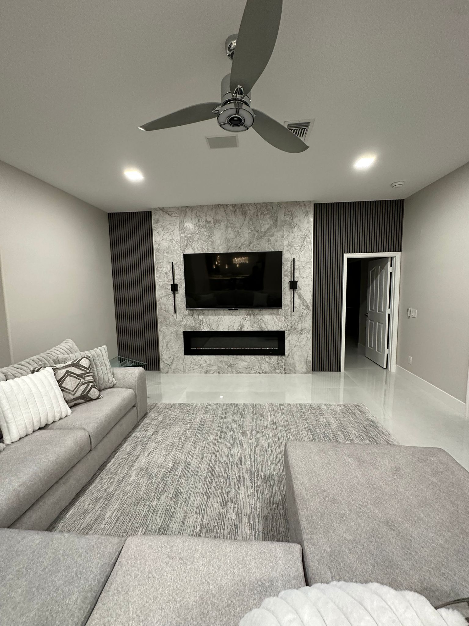 A living room with a ceiling fan and a flat screen tv.