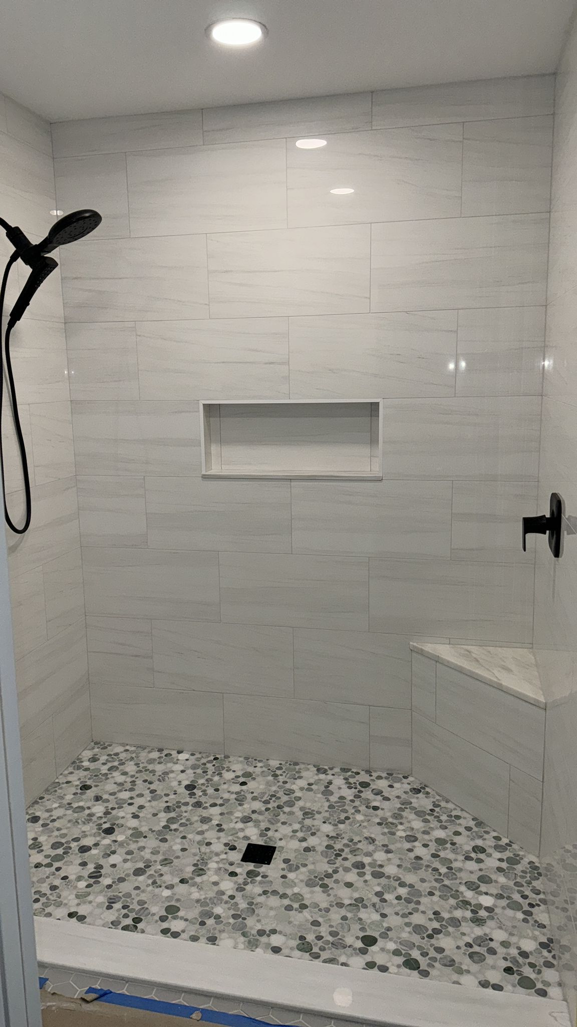 A shower  in Palm Beach County with white tiles and a black shower head.