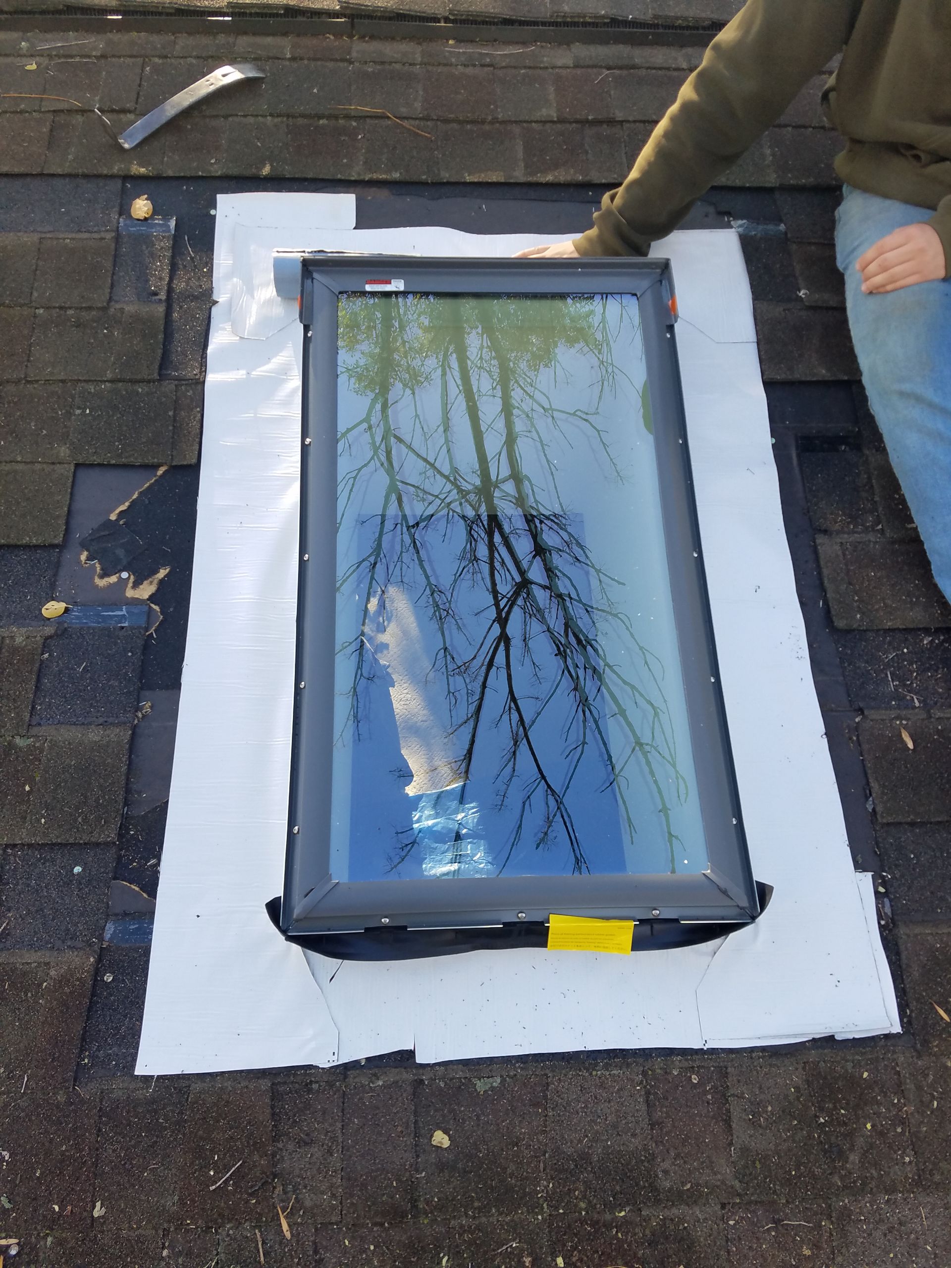 A man is working on a skylight on a roof