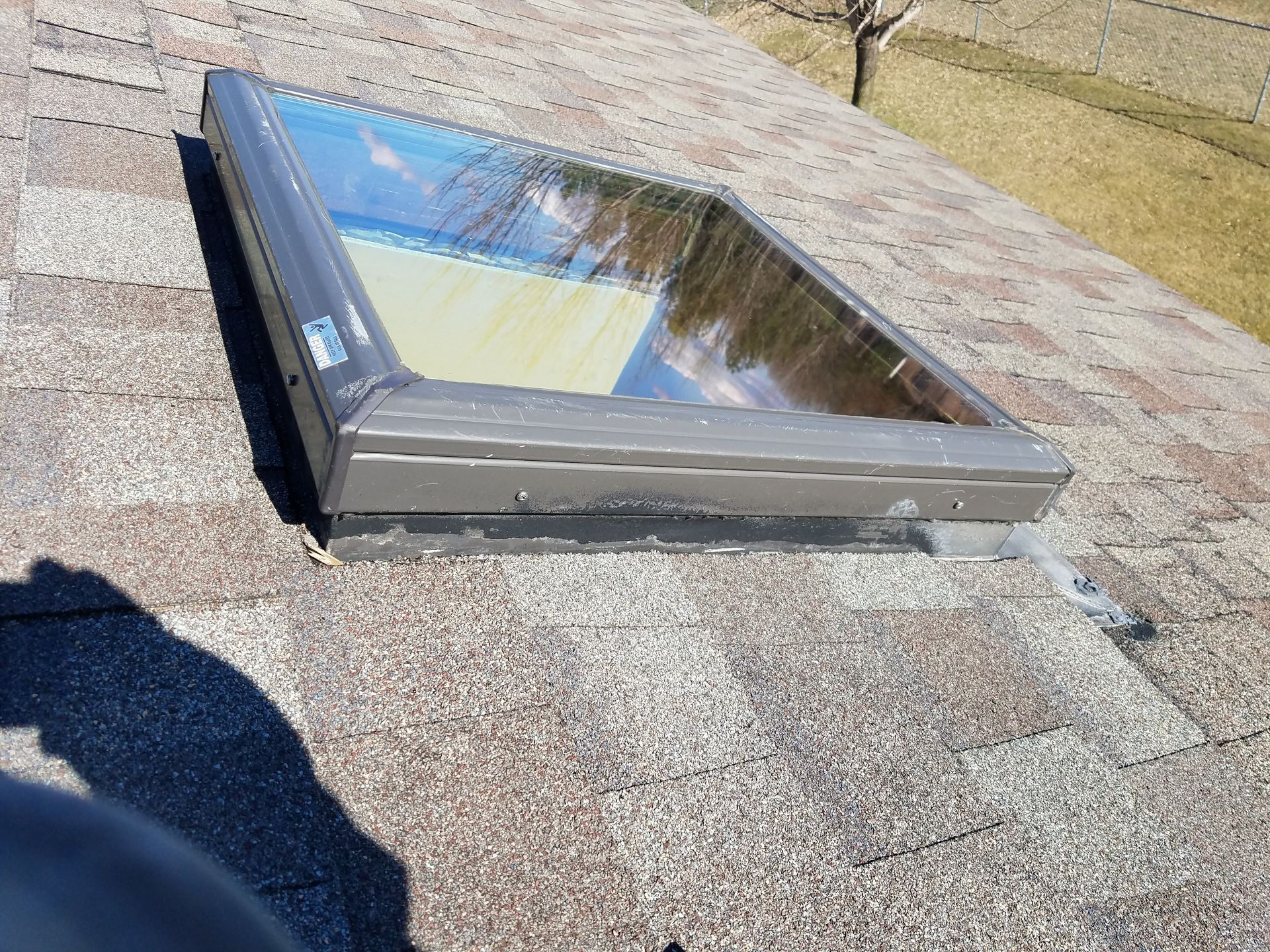 A skylight is sitting on top of a brick roof.