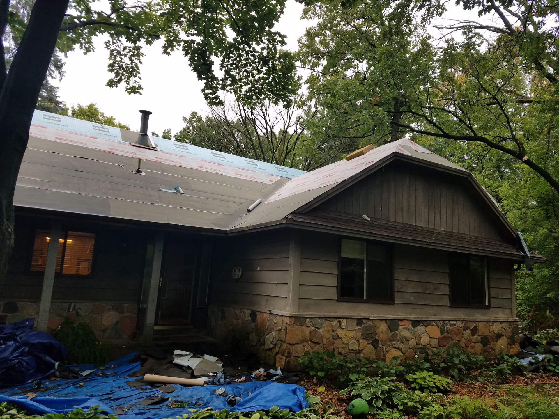 A house with a blue tarp on the ground in front of it