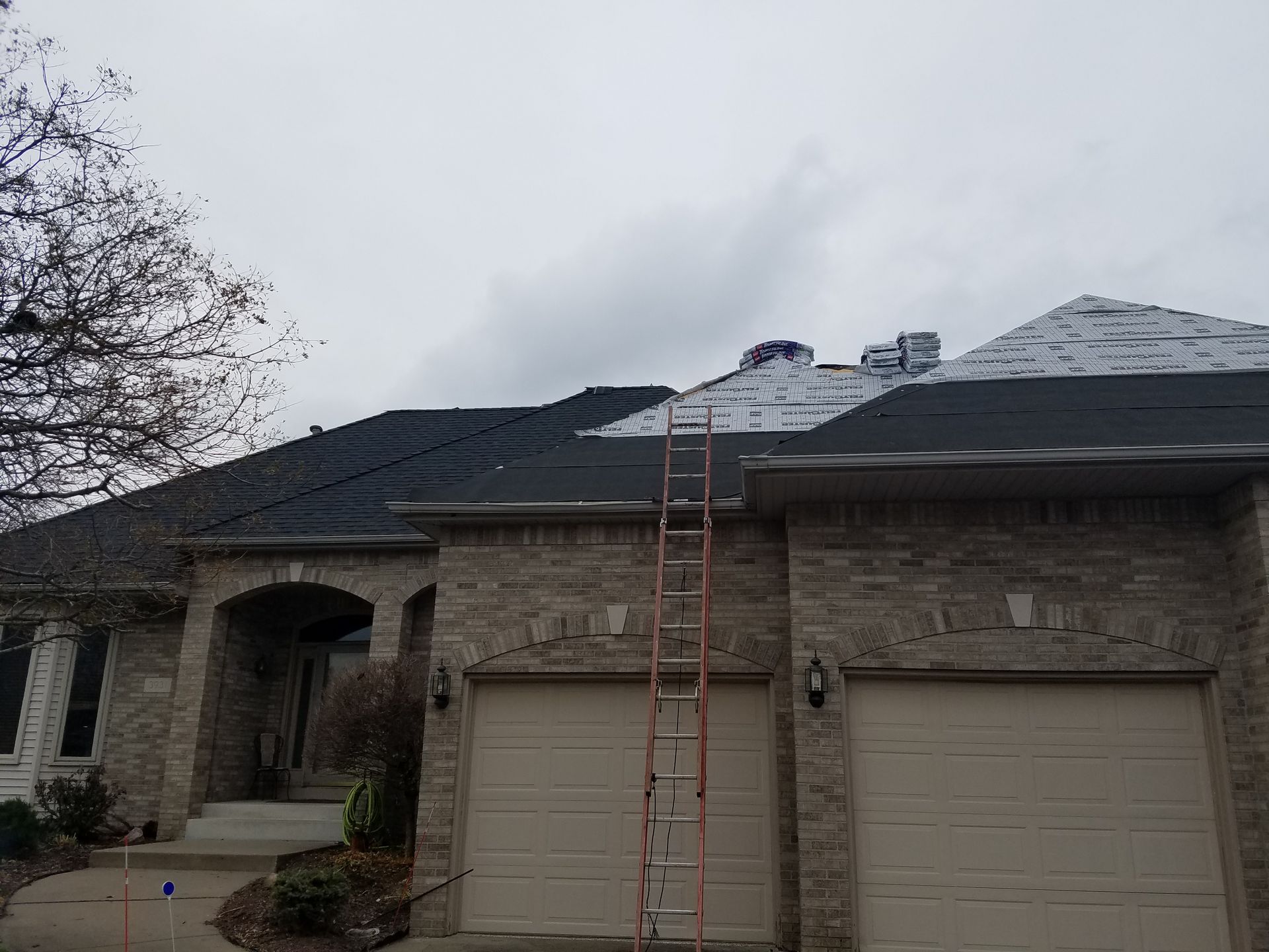 A house with two garage doors and a ladder on the roof.