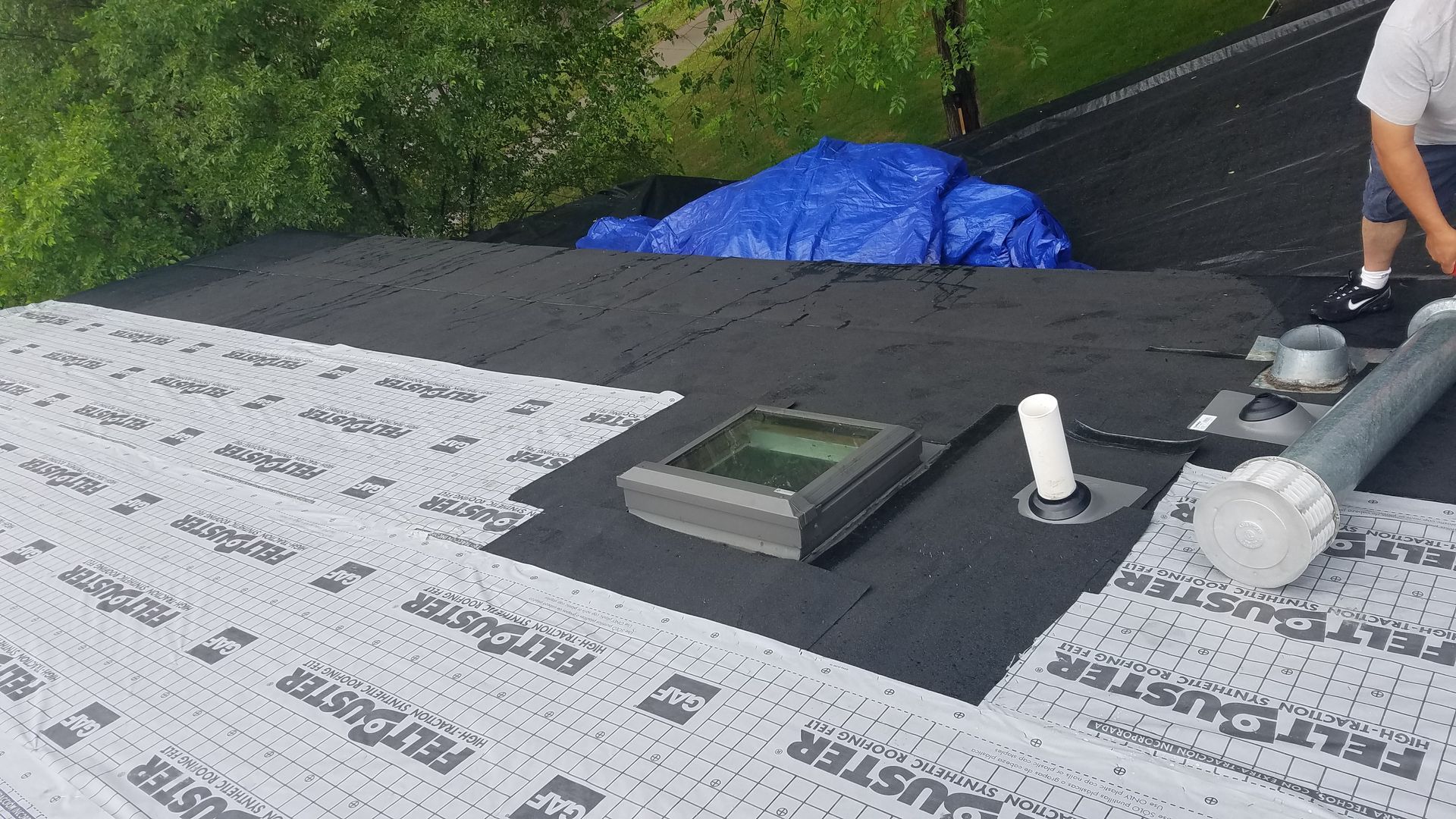 A man is working on a roof with a skylight.