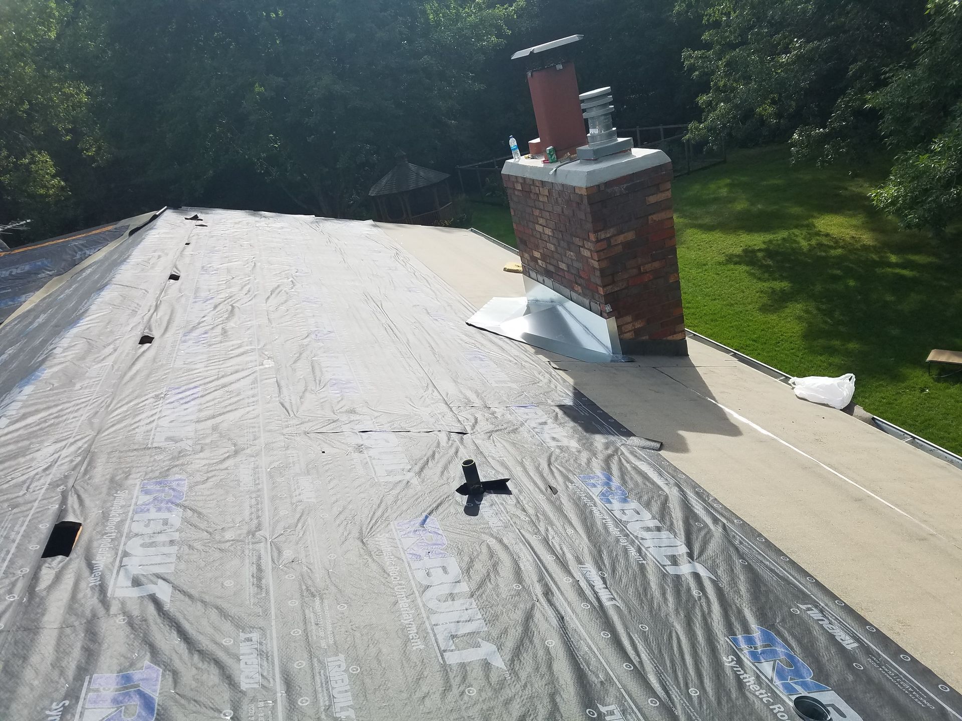 A roof with a chimney and a tarp on it