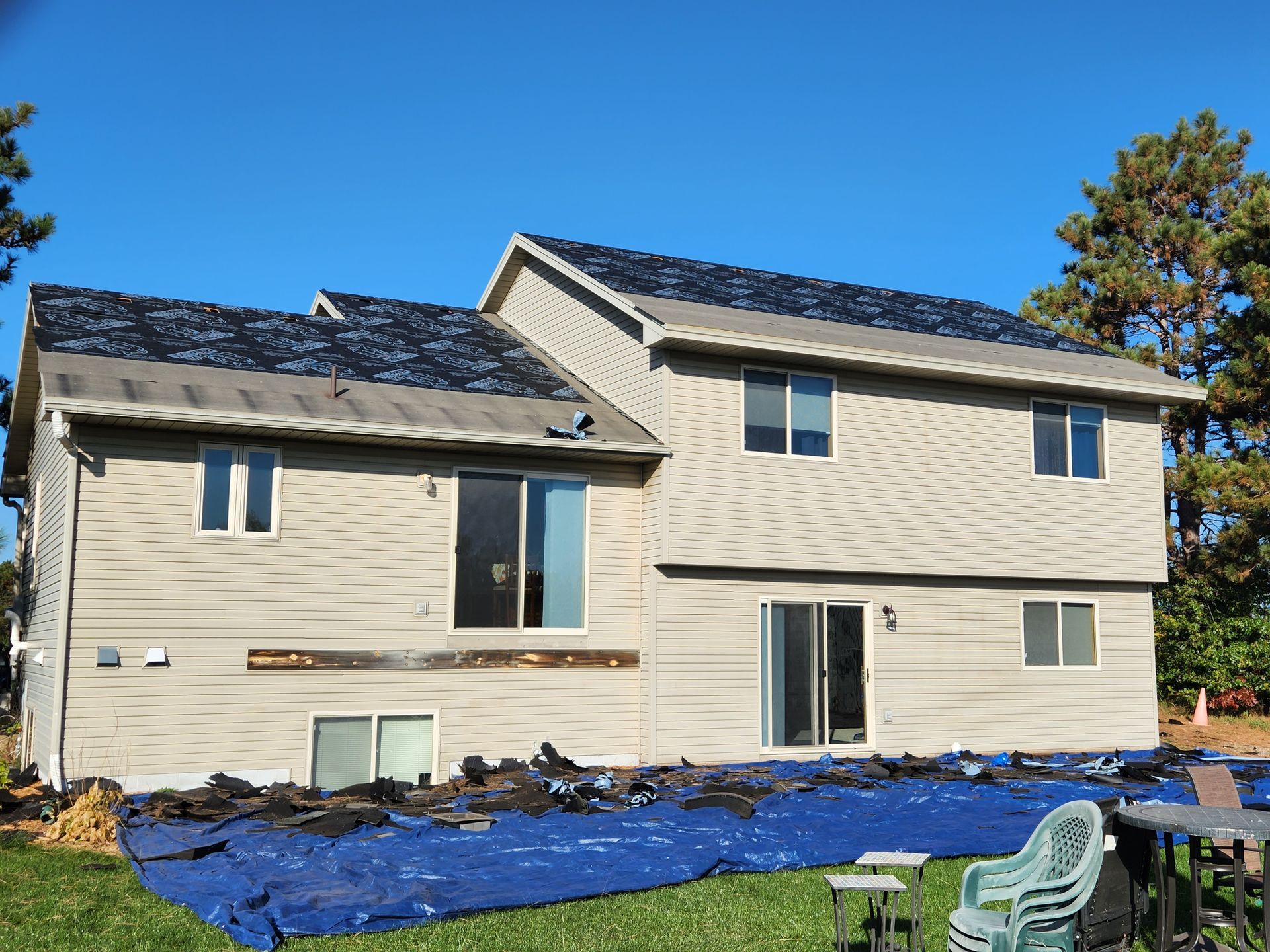 A house with a blue tarp on the ground in front of it