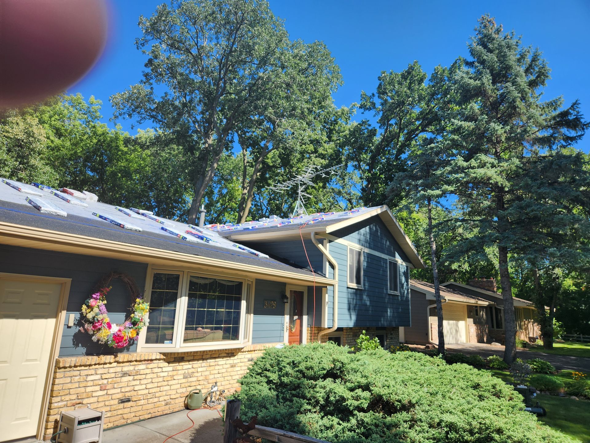 A house with a roof that is being installed is surrounded by trees.