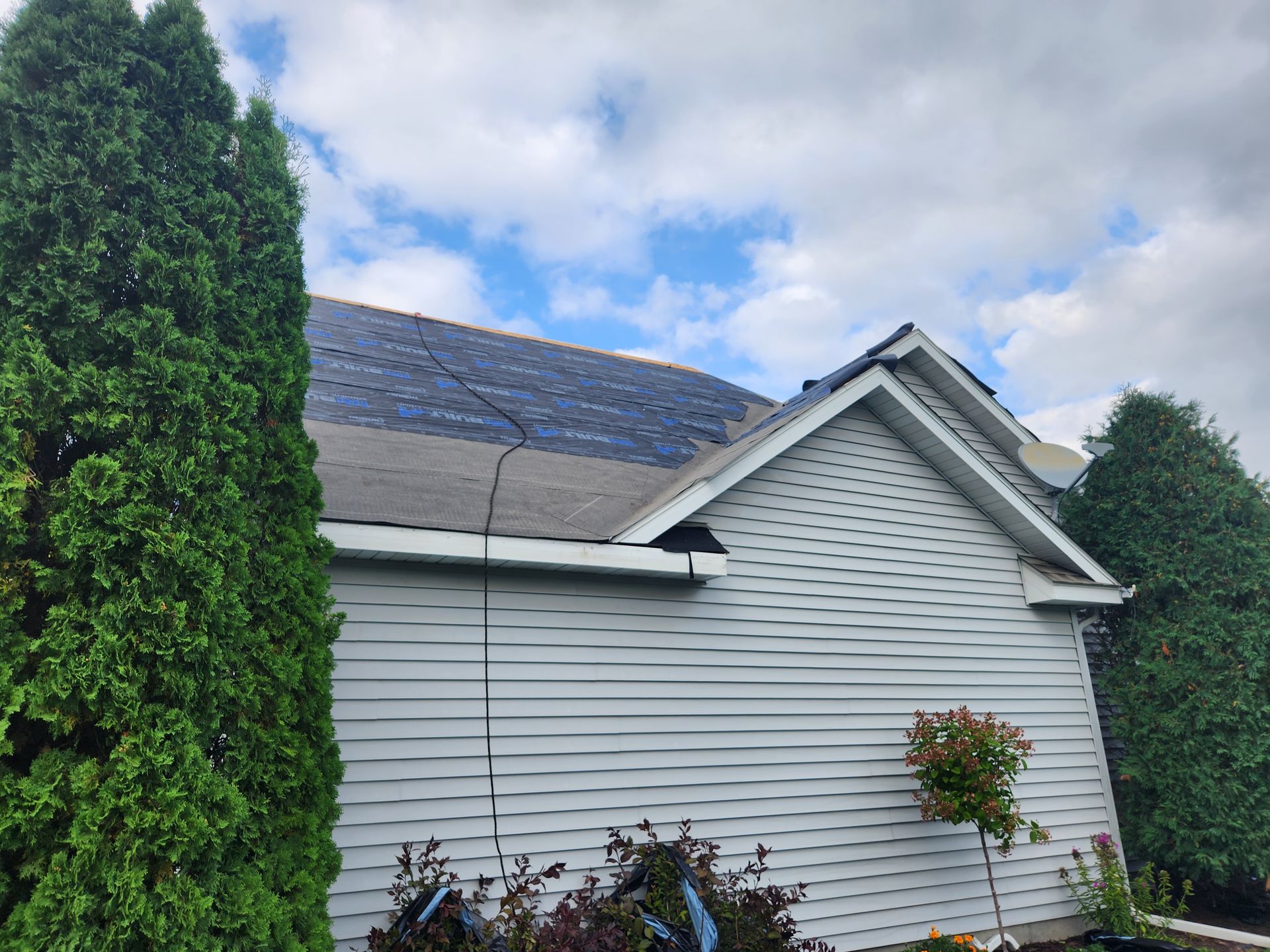 A white house with a roof that is being repaired.