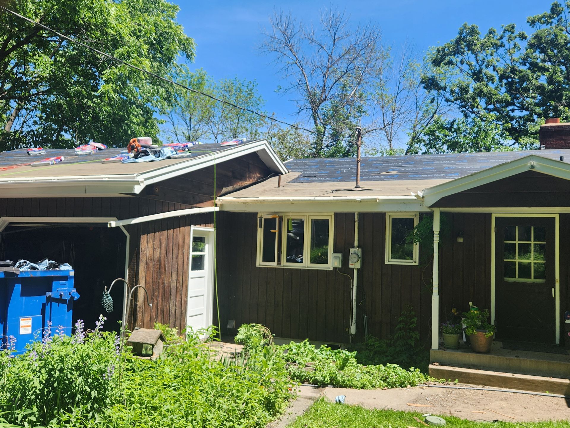 A brown house with a blue trash can in front of it