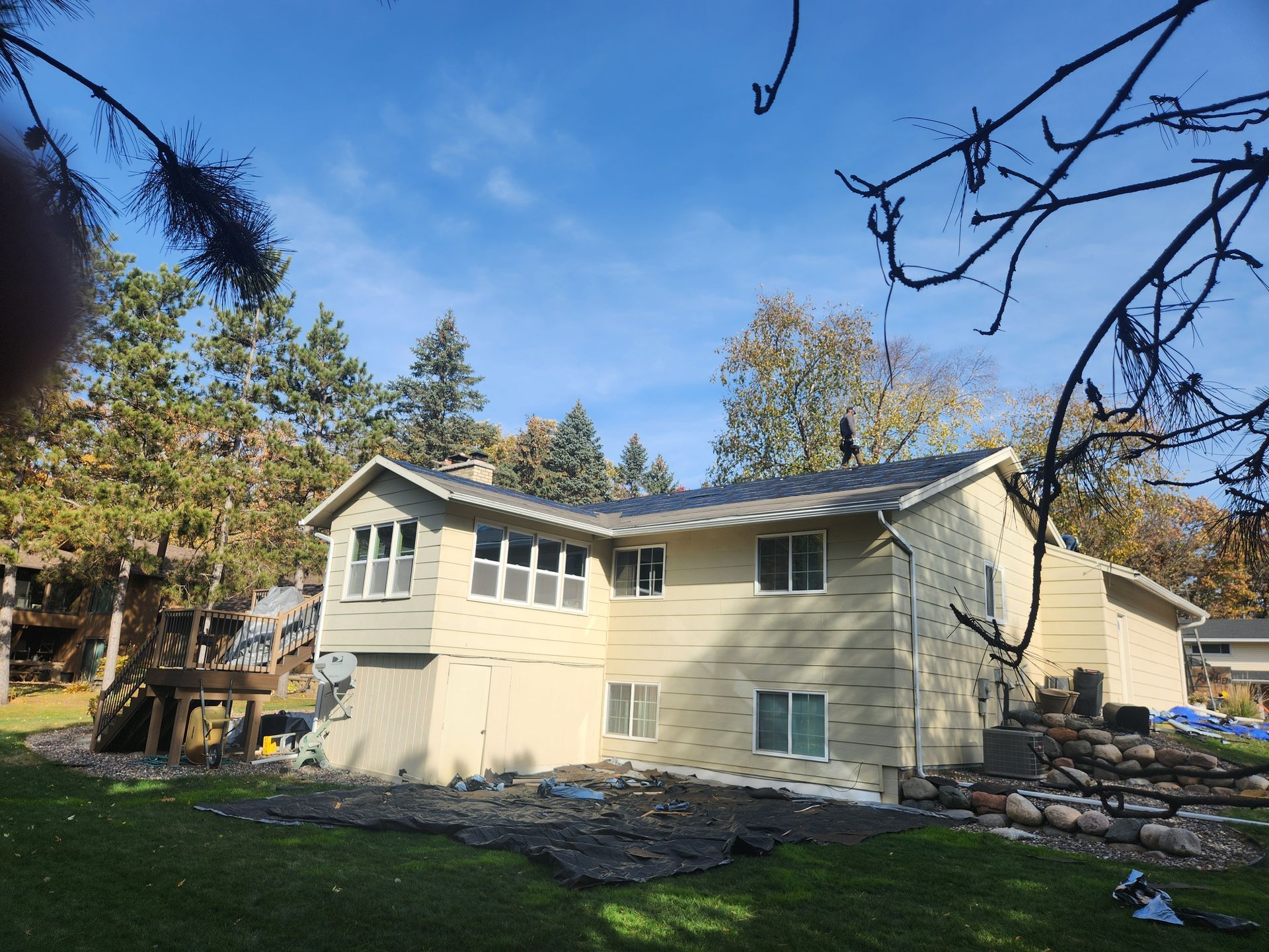 A large house with a lot of windows is surrounded by trees on a sunny day.
