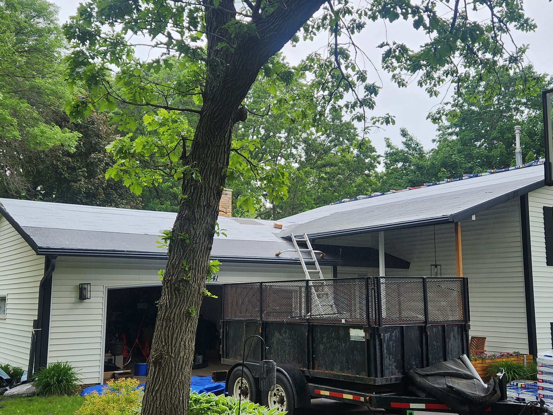 A white house with a metal roof and a trailer parked in front of it.