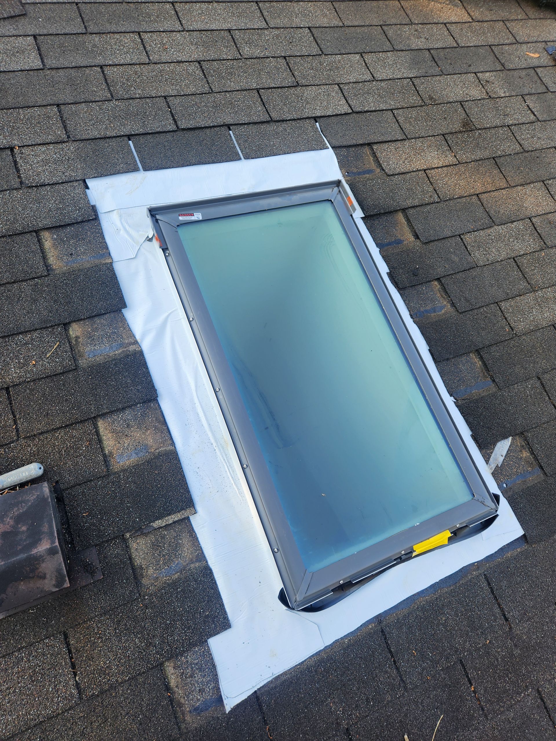 A skylight is sitting on top of a brick roof.