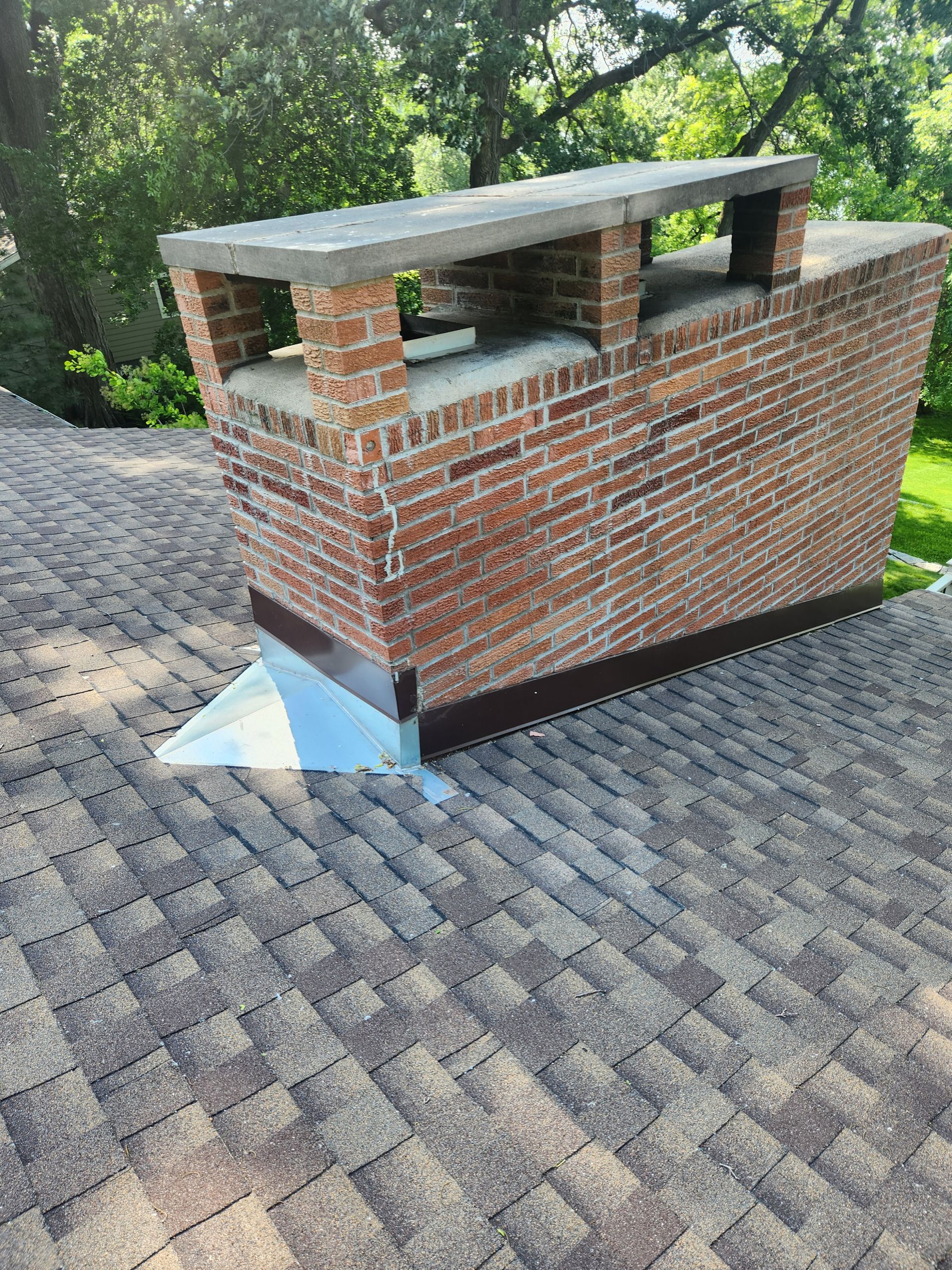 A brick chimney is sitting on top of a roof.