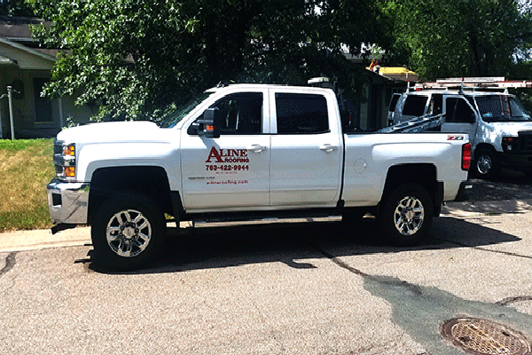 A white aline truck is parked in front of a house