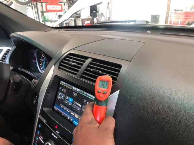 A person is using a thermometer to check the temperature of a car