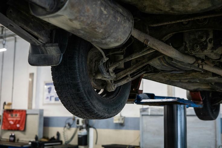 A car is sitting on a lift in a garage.