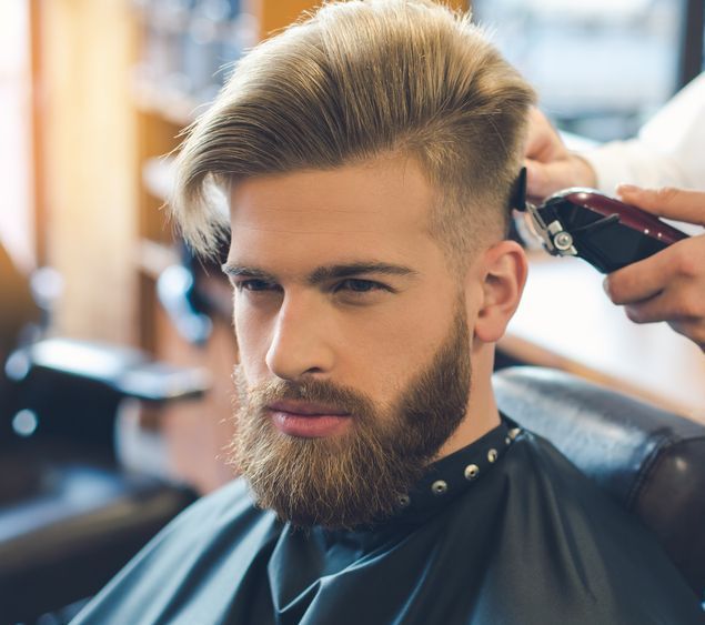A Young Boy is Getting His Hair Cut by a Barber With a Clipper — Dudes n Dolls Hair Lounge In Warners Bay, NSW