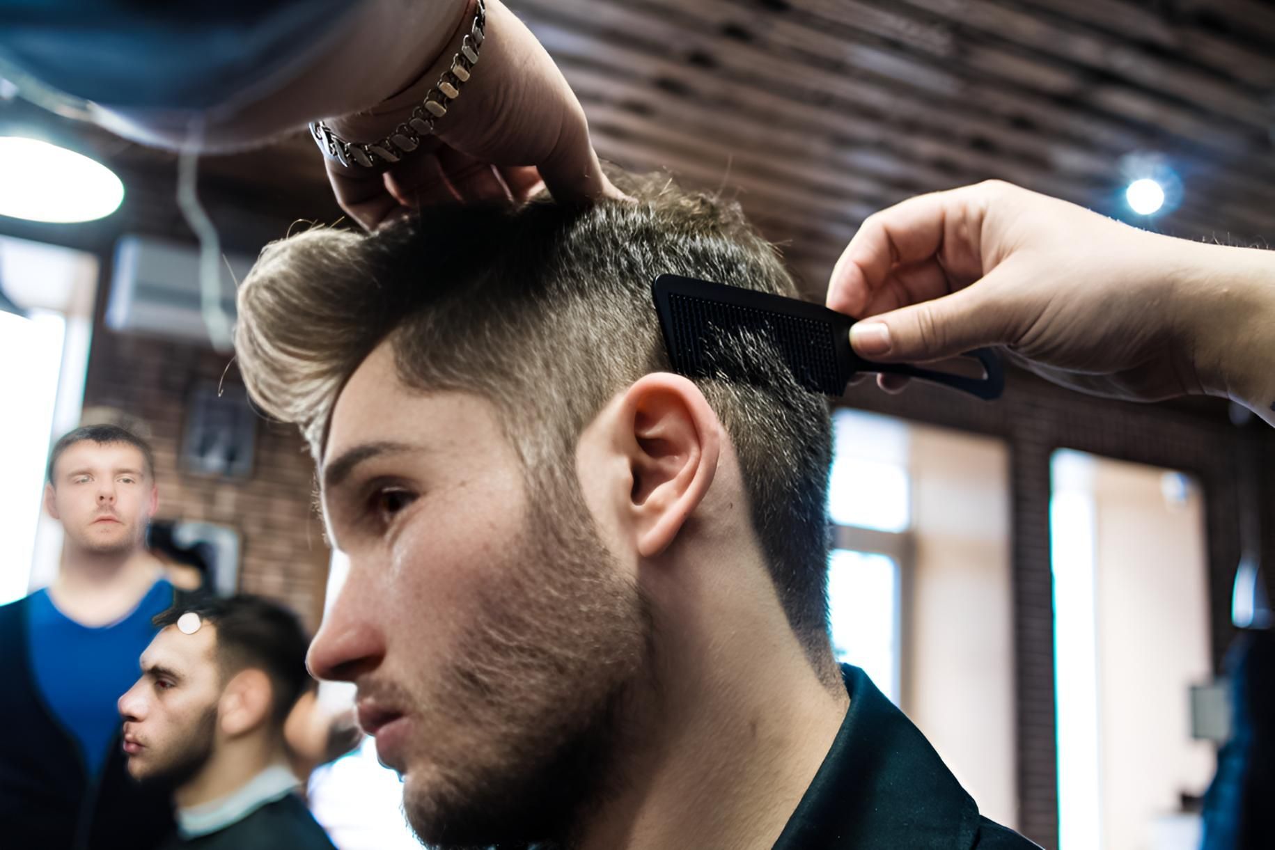 A Man is Getting His Hair Cut by a Barber in a Barber Shop — Dudes n Dolls Hair Lounge In Warners Bay, NSW