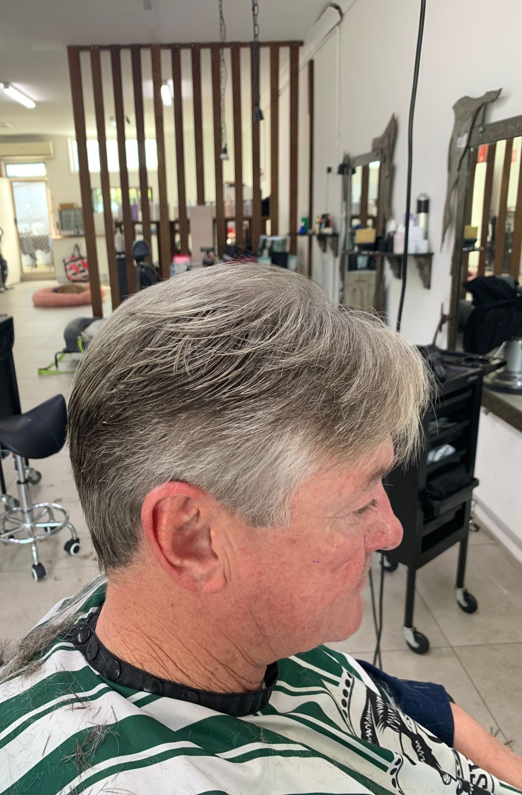 A Little Boy is Getting His Hair Cut by a Woman at a Hair Salon — Dudes n Dolls Hair Lounge In Warners Bay, NSW
