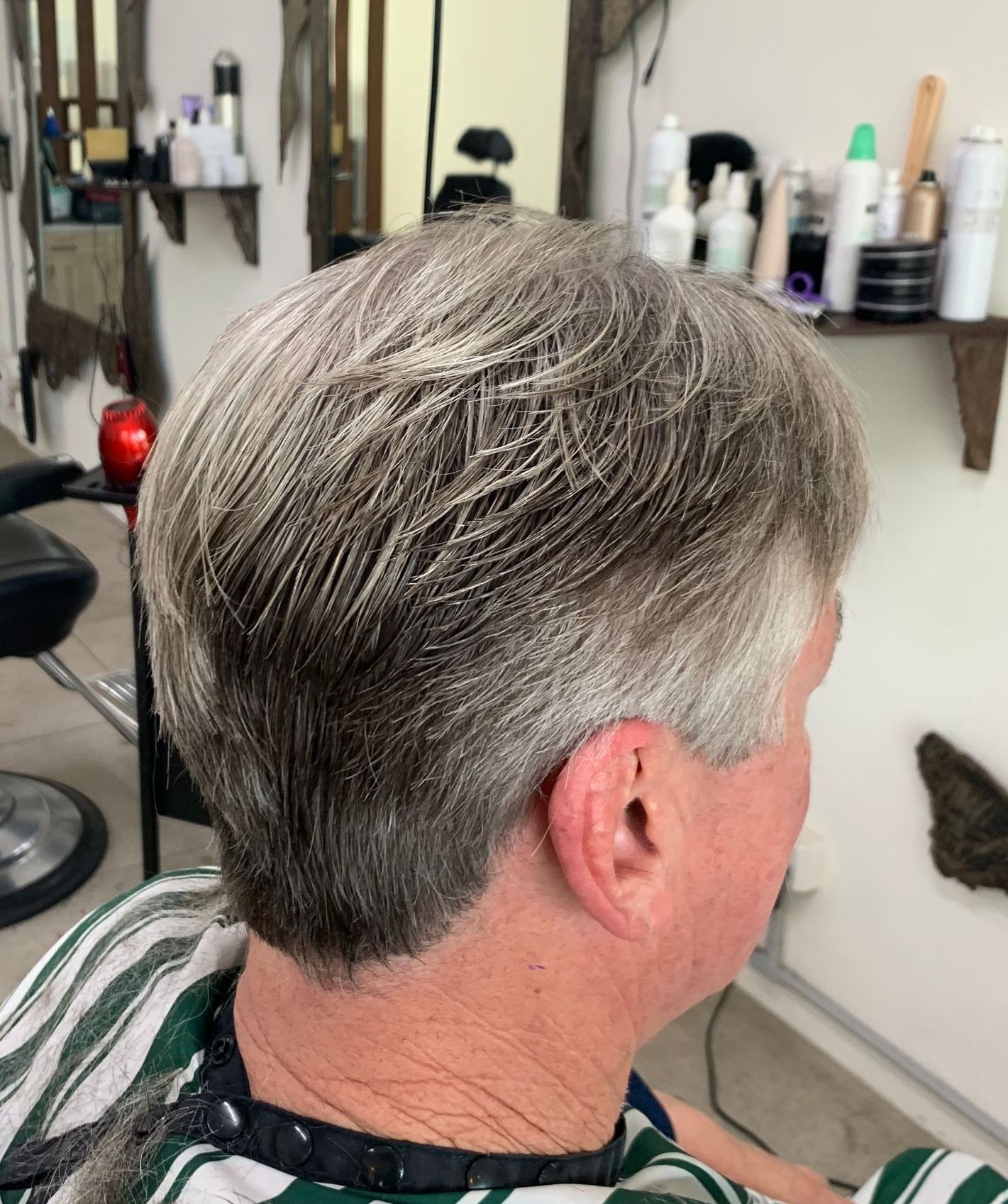 A Man With a Beard is Getting His Hair Cut by a Barber in a Barber Shop — Dudes n Dolls Hair Lounge In Warners Bay, NSW