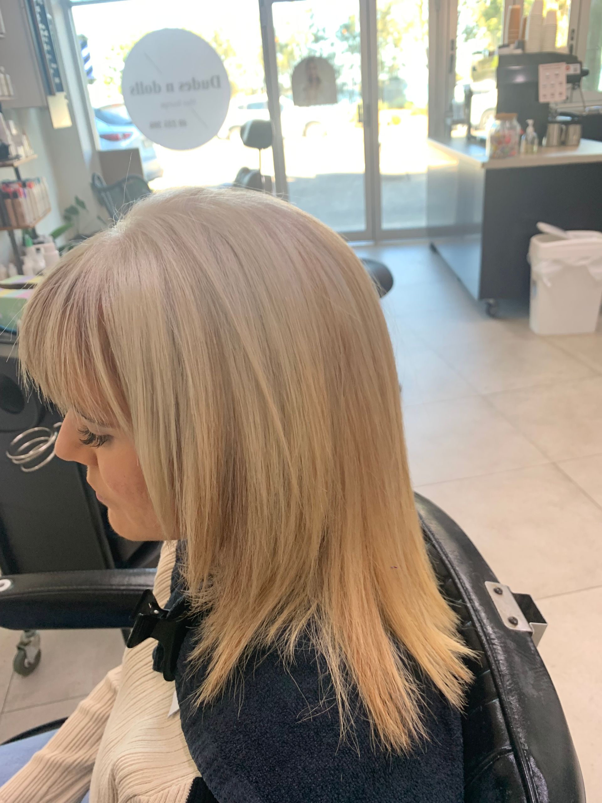 A Woman is Getting Her Hair Done by a Hairdresser in a Salon — Dudes n Dolls Hair Lounge In Warners Bay, NSW