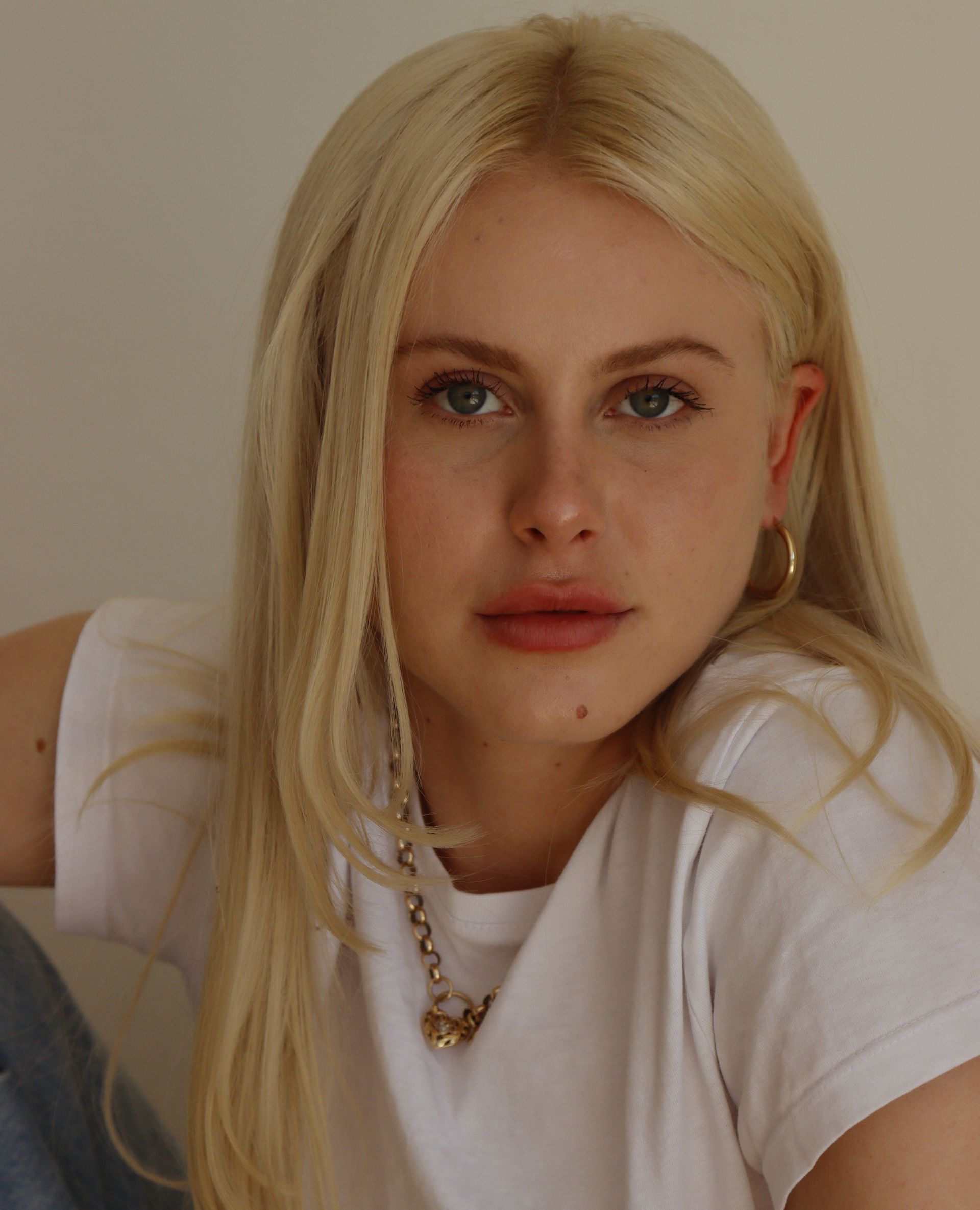 Blonde woman with fair skin, looking directly at the camera. She wears a white t-shirt and a necklace — Dudes n Dolls Hair Lounge In Warners Bay, NSW