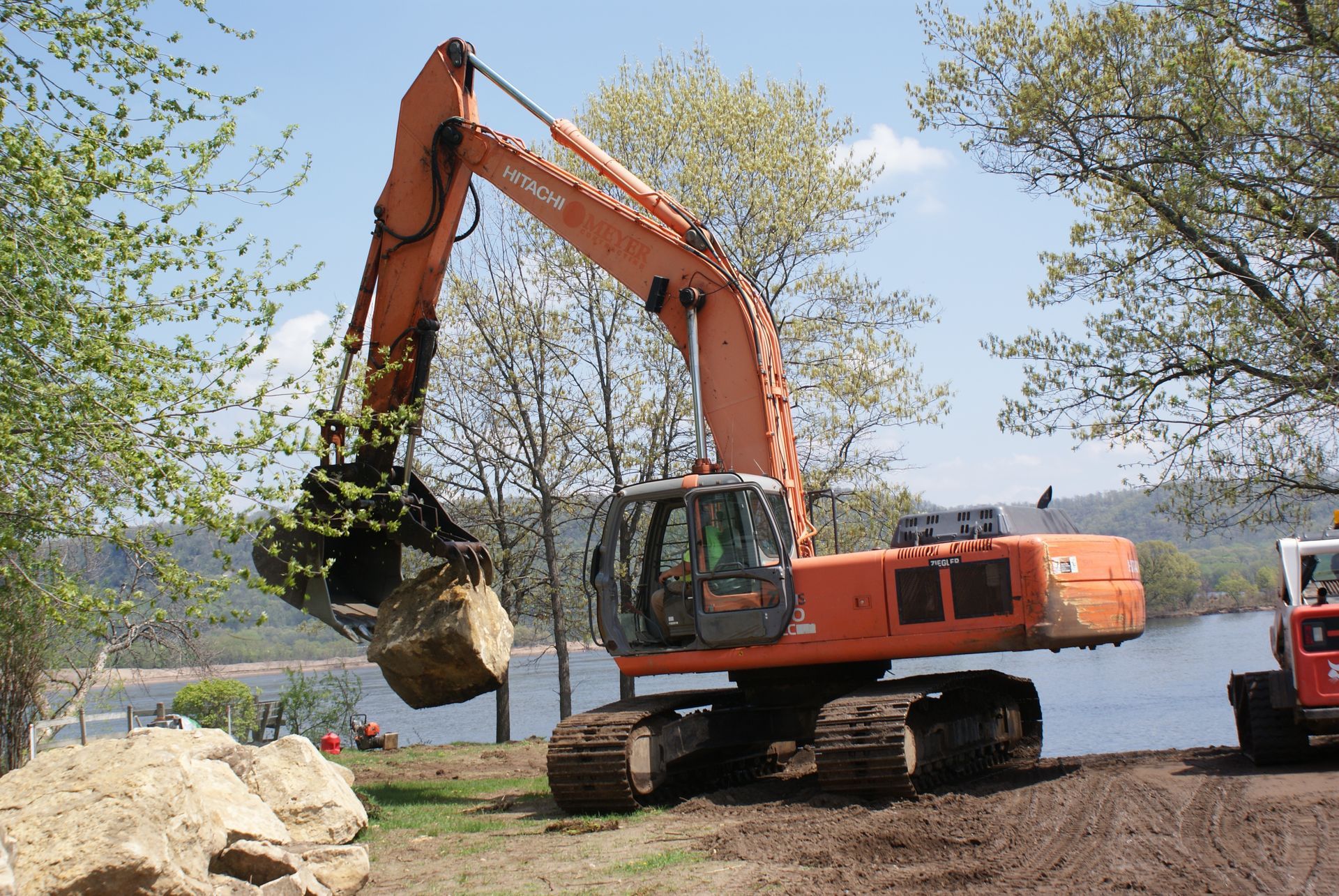 Excavator Lifting Rocks — Kellogg, MN — Danckwart Landscaping LLC