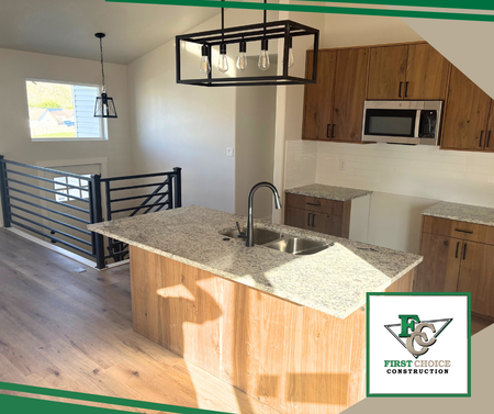 Modern kitchen with wood cabinets, granite island, black railings, and pendant light.