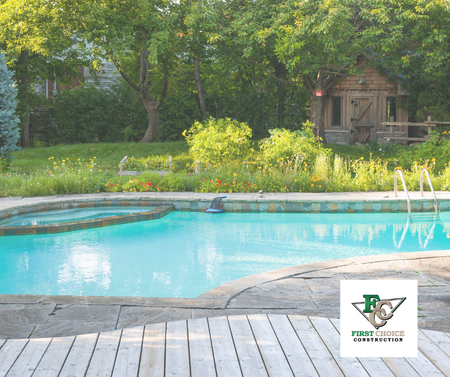 Backyard swimming pool with blue water, stone deck, and trees in the background