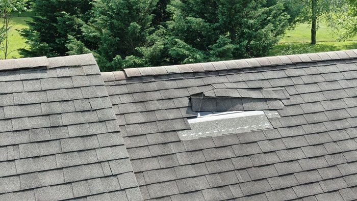 A roof with a hole in it and trees in the background.