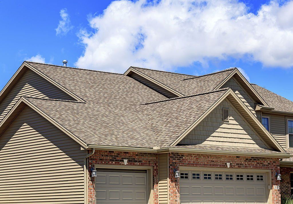 The roof of a house with a garage door and a blue sky in the background.