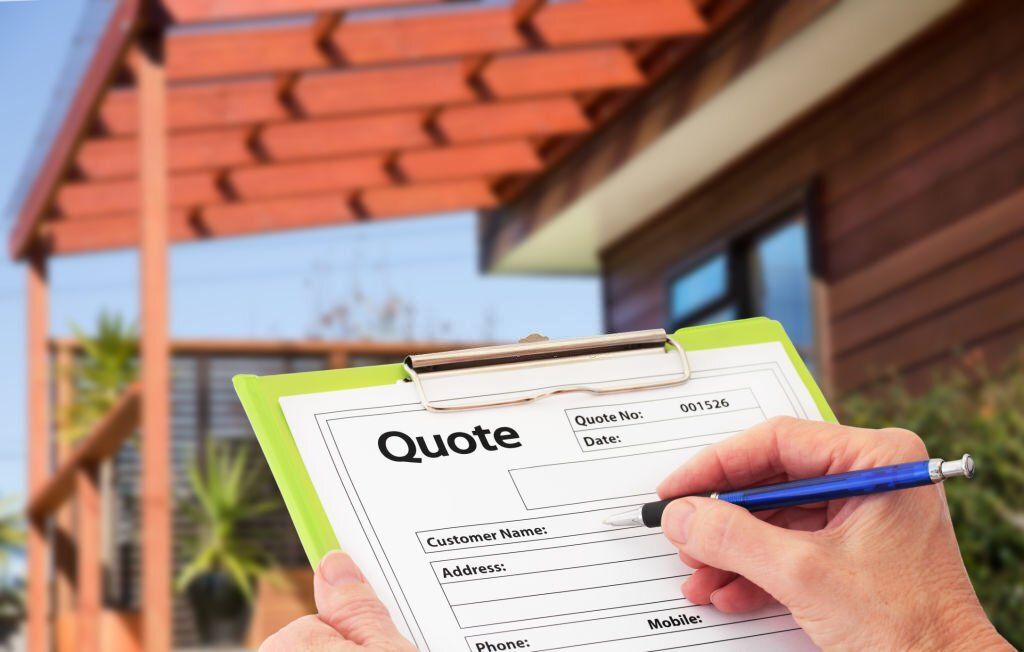 A person is writing on a clipboard in front of a house.