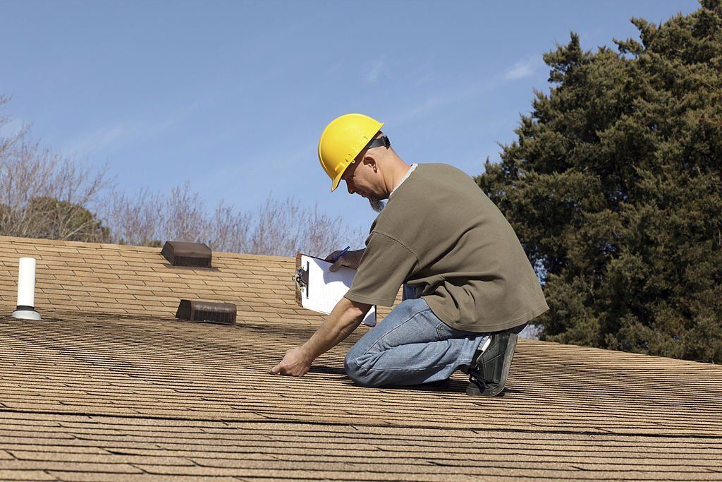 A man wearing a hard hat is working on a roof