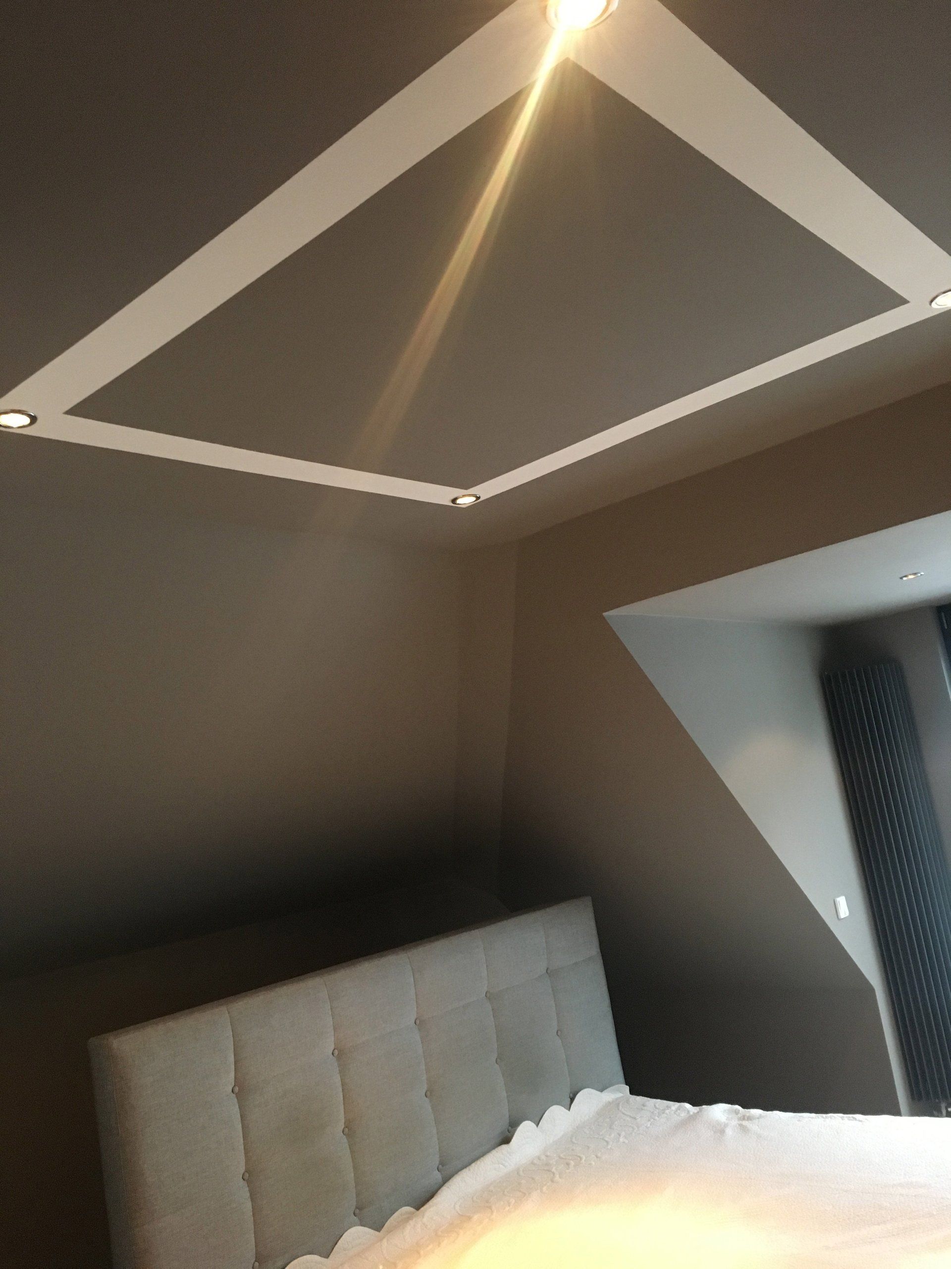 Graue Wand in Schlafzimmer mit eckigem Muster an Decke