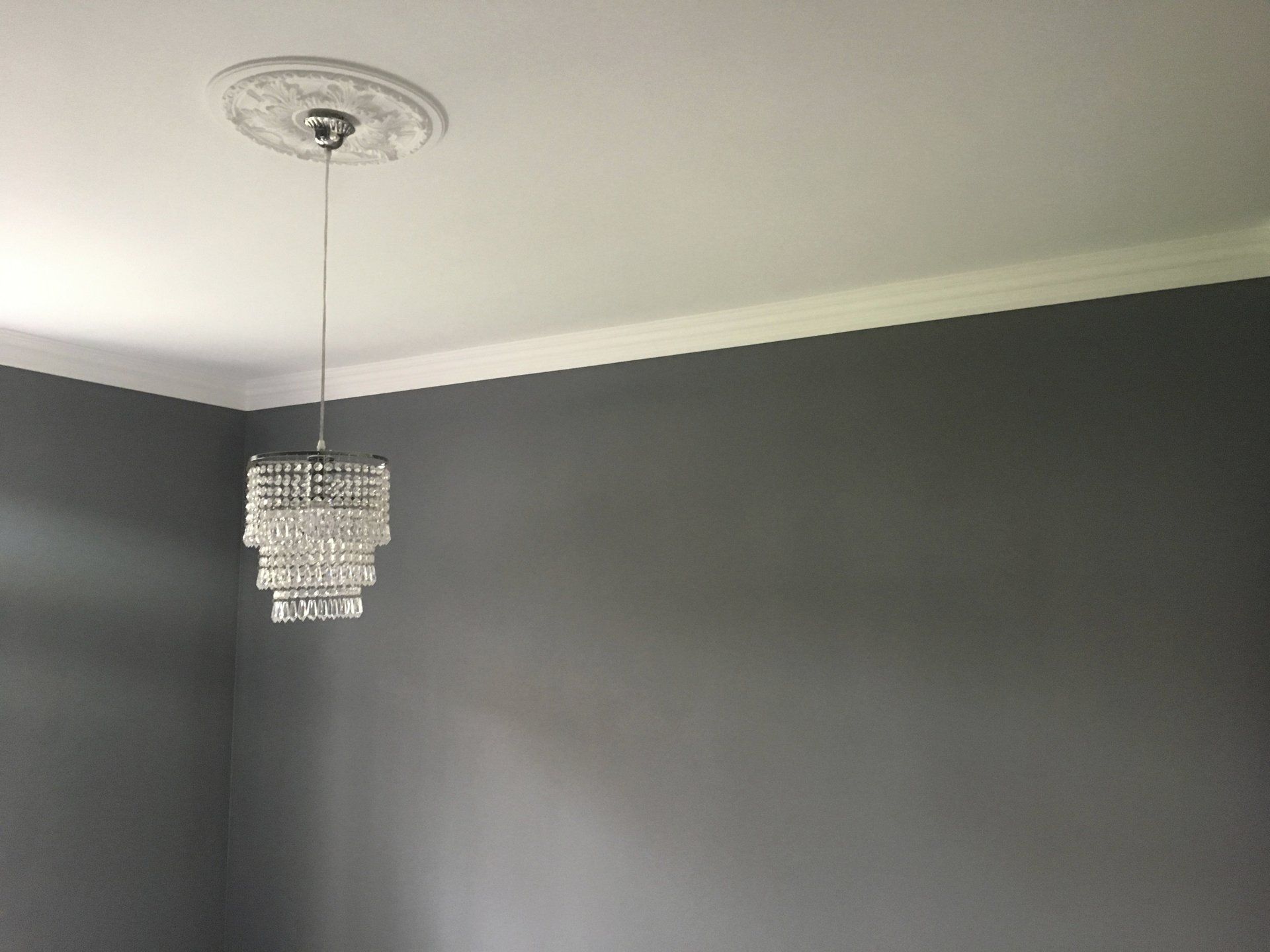 Graue Wand und Kronleuchter an Decke